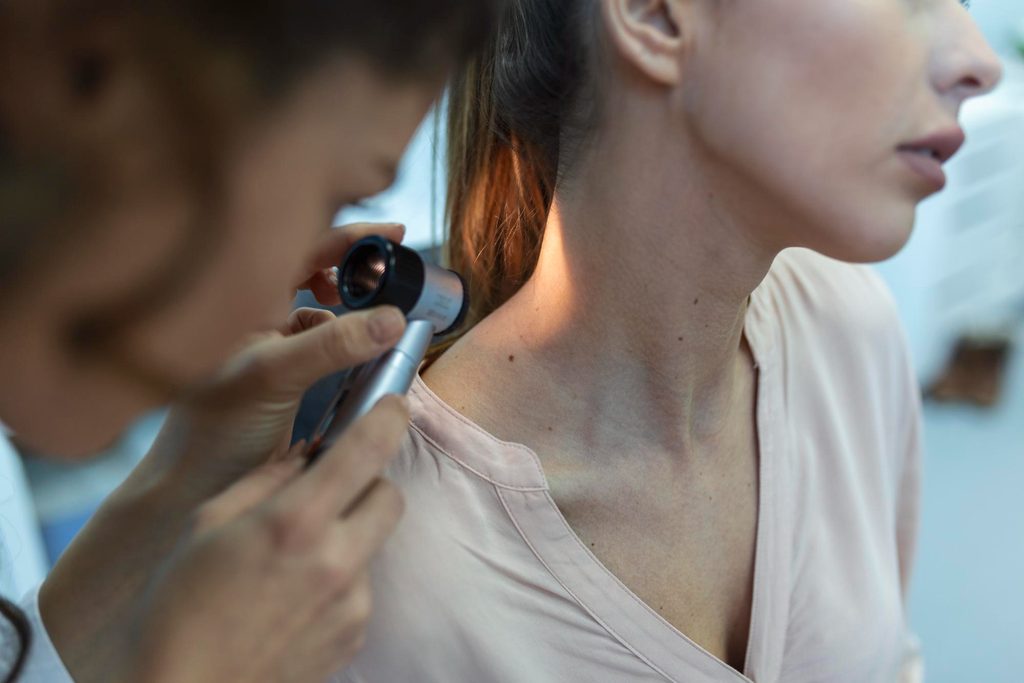 Medic care evalueaza un papilom, folosind un dermatoscop